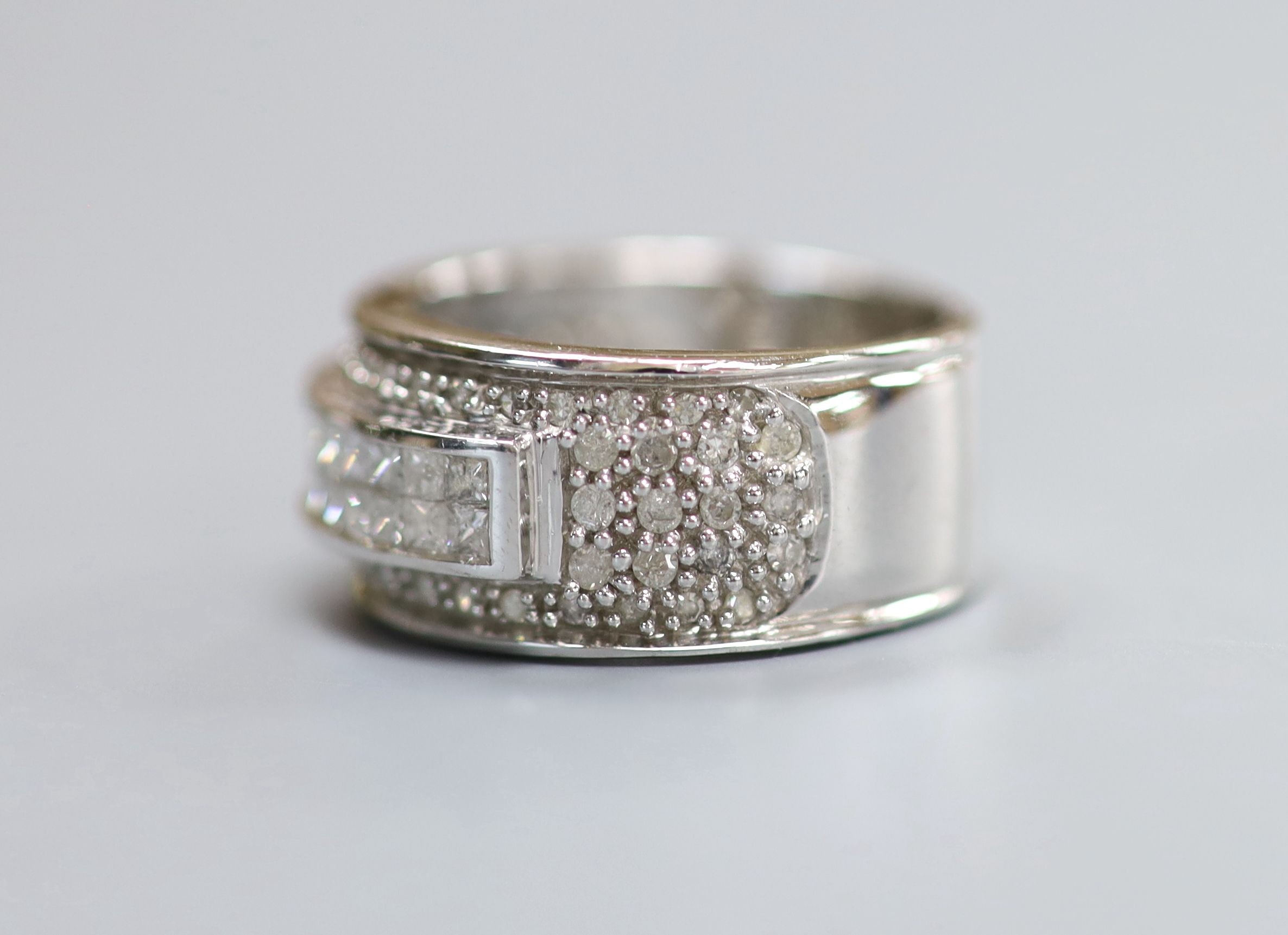 A modern 9ct white gold and fancy cut diamond channel set dress ring with diamond chip cluster setting, size L, gross weight 6.8 grams.